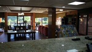 Un hall de hotel con zona de comedor, asientos y una exhibición de revistas.