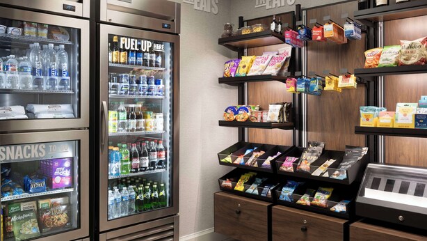 Un área de venta automática con aperitivos, bebidas y un refrigerador que dice 'Recarga Aquí'.