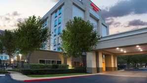 Un hotel moderno con un letrero llamativo, un acceso cubierto y jardines bien cuidados.