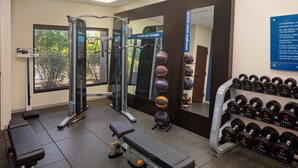 Uma academia com equipamentos de ginástica, um banco e uma barra com halteres.