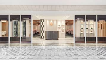 A modern hotel lobby with a check-in counter, seating area, and a patterned floor.