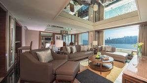 A spacious hotel living room with a large sofa set, a coffee table, and a view of the city skyline. - InterContinental Grand Stanford Hong Kong by IHG (Kowloon)