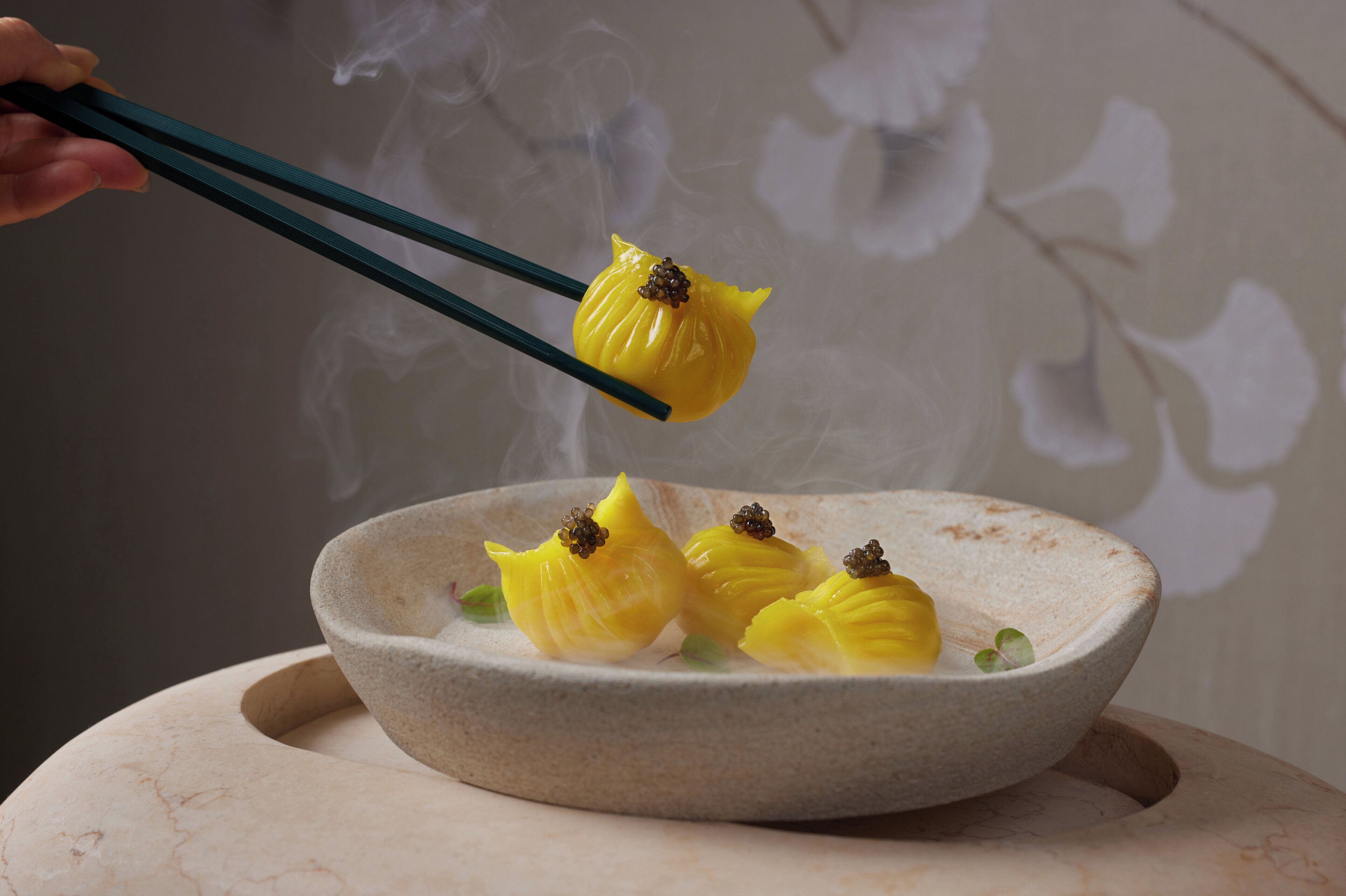 A bowl of dumplings with chopsticks lifting one.