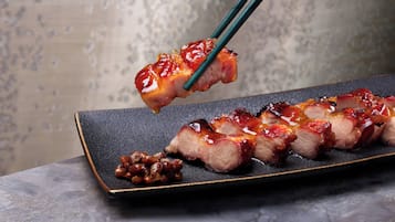 Un plato de carne en rodajas con un glaseado, acompañado de un puñado de frijoles.