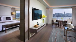 A modern hotel room with a bed, a desk, a TV, and a dining area with a view of the city skyline. - InterContinental Grand Stanford Hong Kong by IHG (Kowloon)