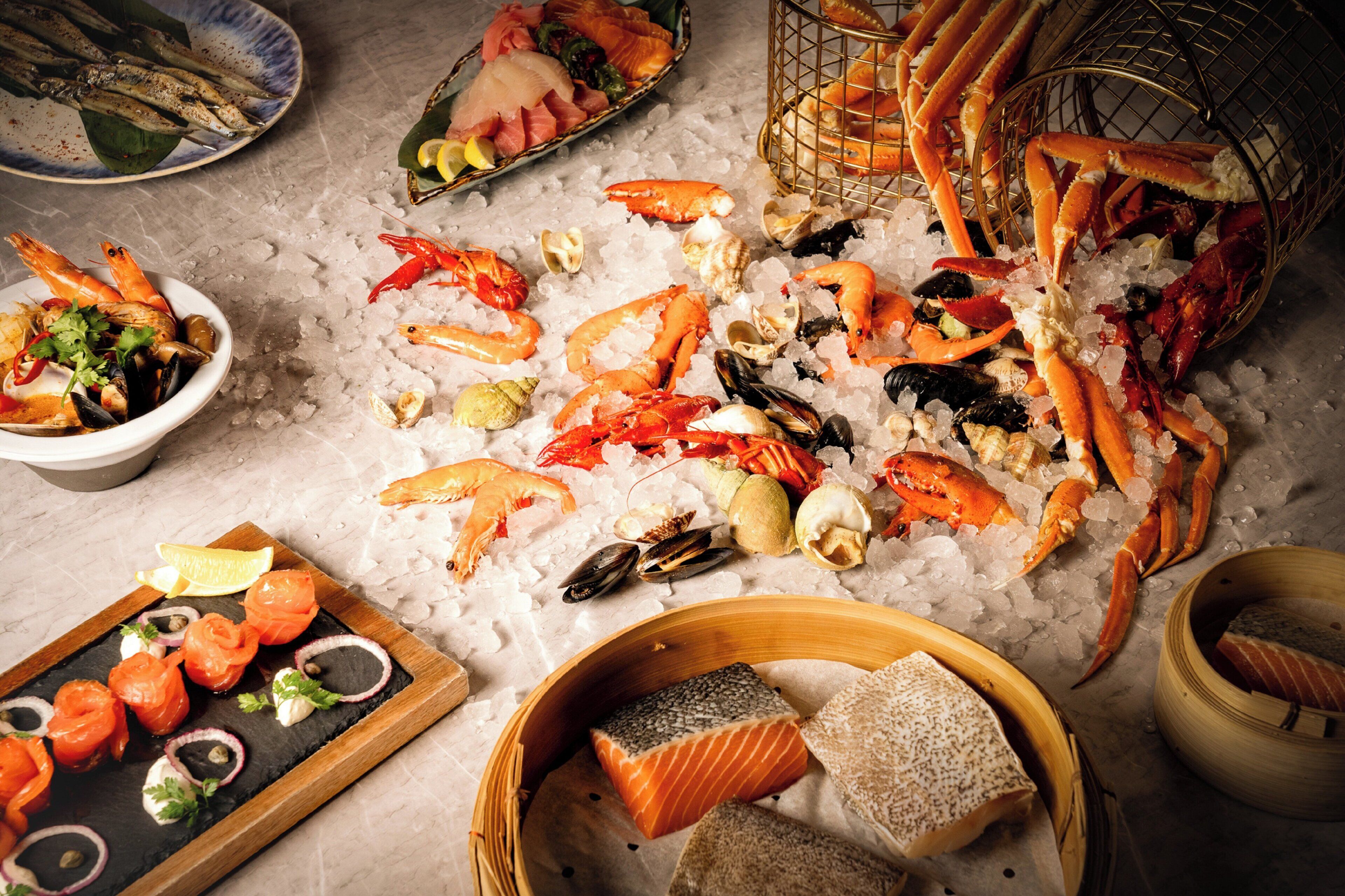 A variety of seafood on ice, including shrimp, crab, and salmon, arranged on a marble surface.