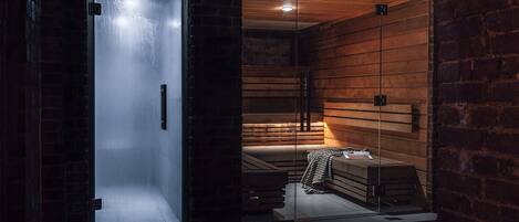 A sauna room with a glass door, wooden benches, and a bench with a striped towel.