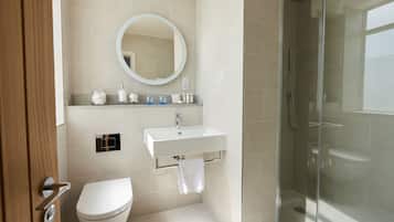 A modern bathroom with a toilet, sink, and glass shower enclosure.