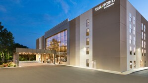 Un moderno edificio de hotel con una amplia fachada de vidrio, una entrada cubierta y un letrero que dice 