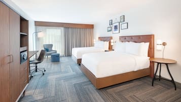 A hotel room with two beds, a desk, a chair, and a small table.