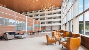 Un vestíbulo amplio con techo alto, mobiliario moderno y ventanas grandes que ofrecen vistas al exterior.
