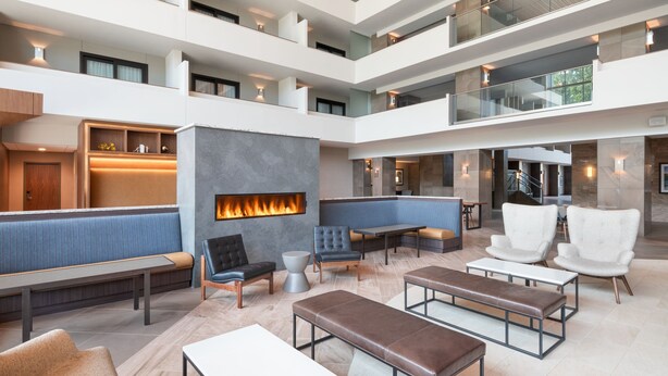 Un vestíbulo de hotel de varios niveles con zonas de estar, una chimenea y una escalera.