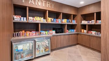 A pantry with shelves stocked with snacks and a refrigerator.