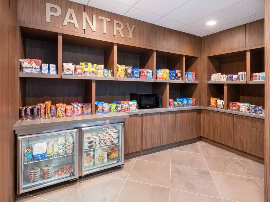 A pantry with shelves stocked with snacks and a refrigerator.