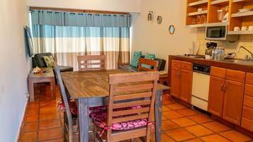 Una cocina compacta con comedor, muebles de madera, microondas y suelo de baldosas.