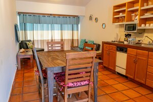Una cocina compacta con comedor, muebles de madera, microondas y suelo de baldosas.