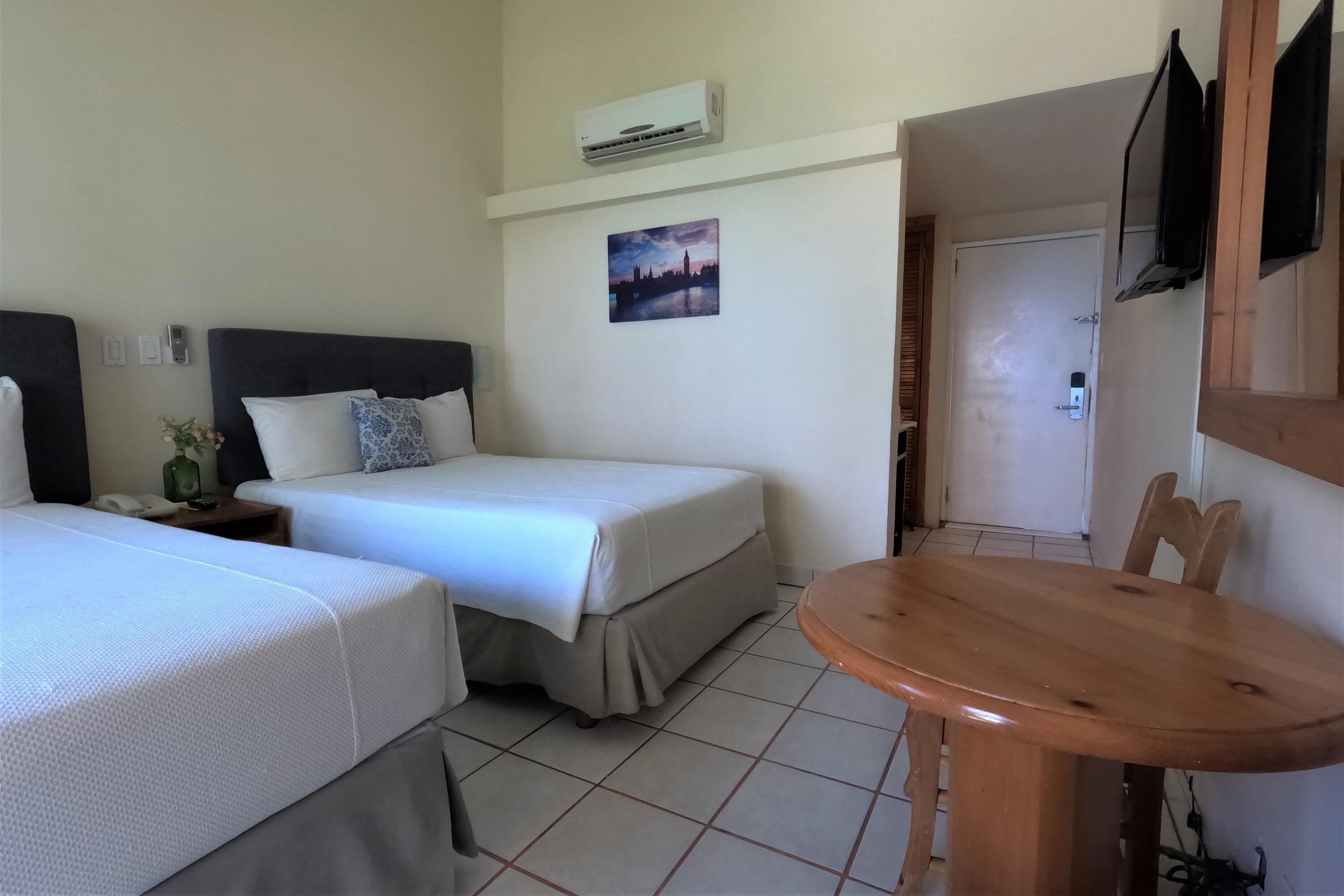 Une chambre d’hôtel avec deux lits, une petite table, un téléviseur et un appareil de climatisation.