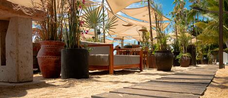 A wooden deck leading to a bed with a view of palm trees and a clear sky.