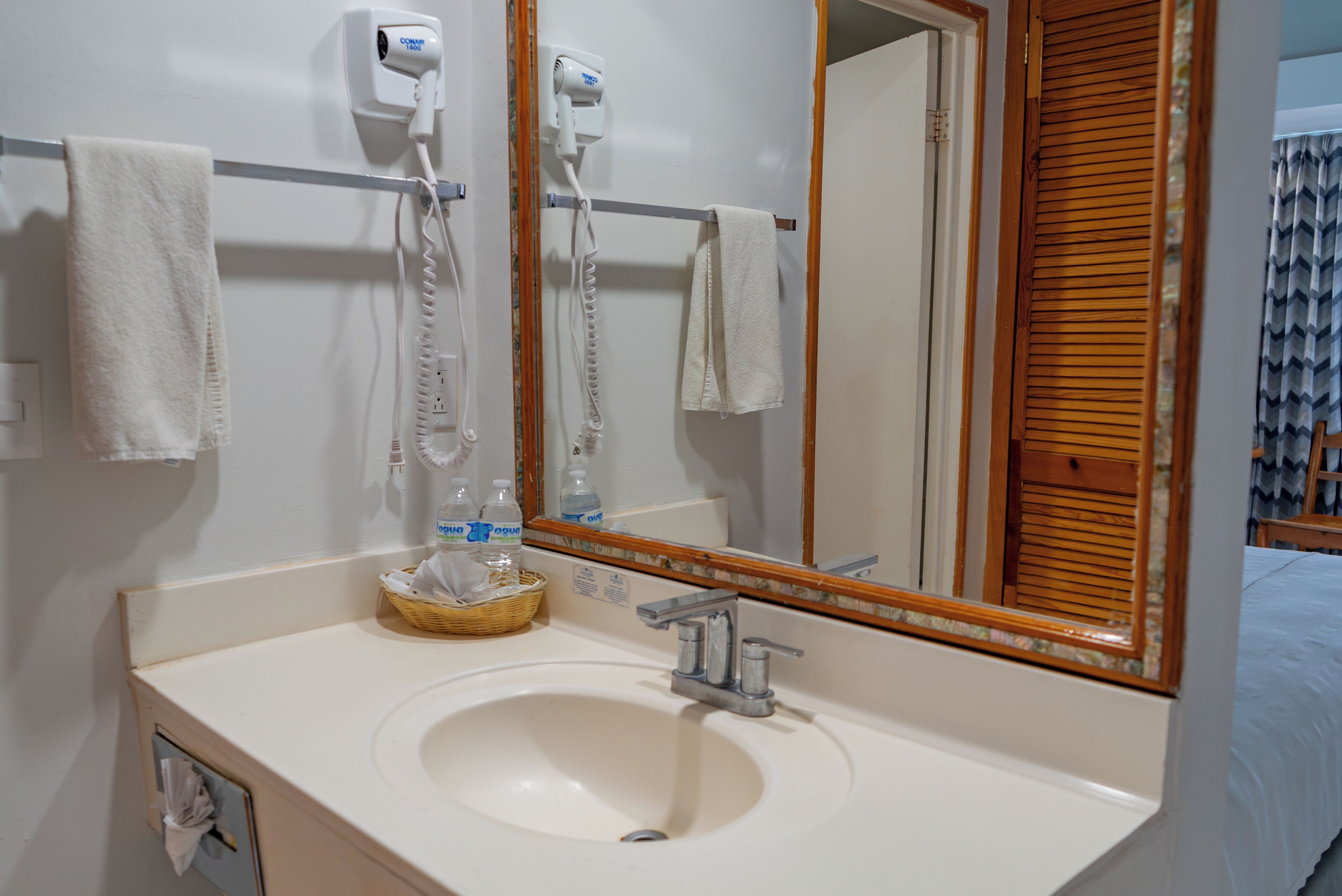 A bathroom with a white sink, a mirror, a hairdryer, and a towel rack.