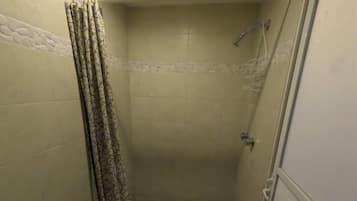 A bathroom with a shower, tiled walls, and a patterned curtain.