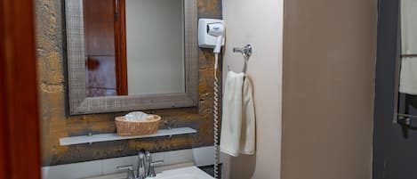 Un bagno con un lavandino bianco, uno specchio, un asciugacapelli e un portasciugamani.