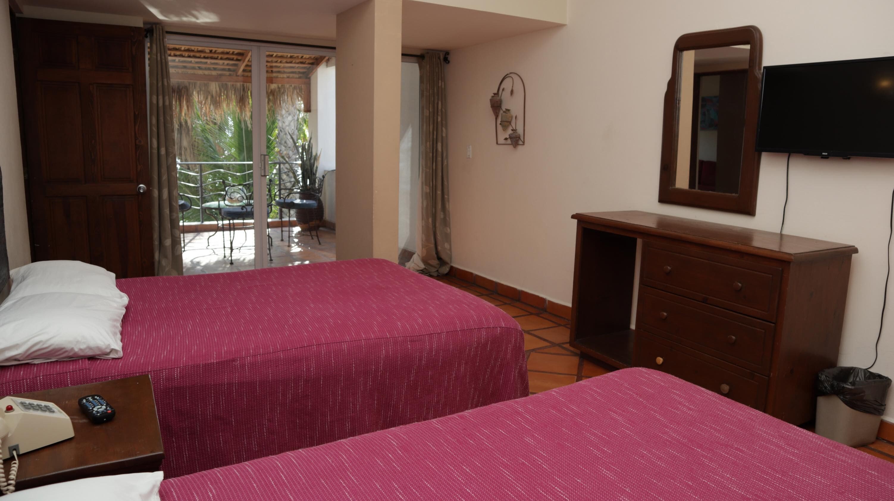 Une chambre d’hôtel avec deux lits, une commode en bois, une télévision et un balcon avec vue.