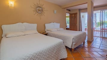 A hotel room with two beds, a sun decoration on the wall, and a view of the outdoor area.