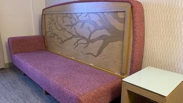 A room with a purple sofa, a small wooden table, and a patterned wall.