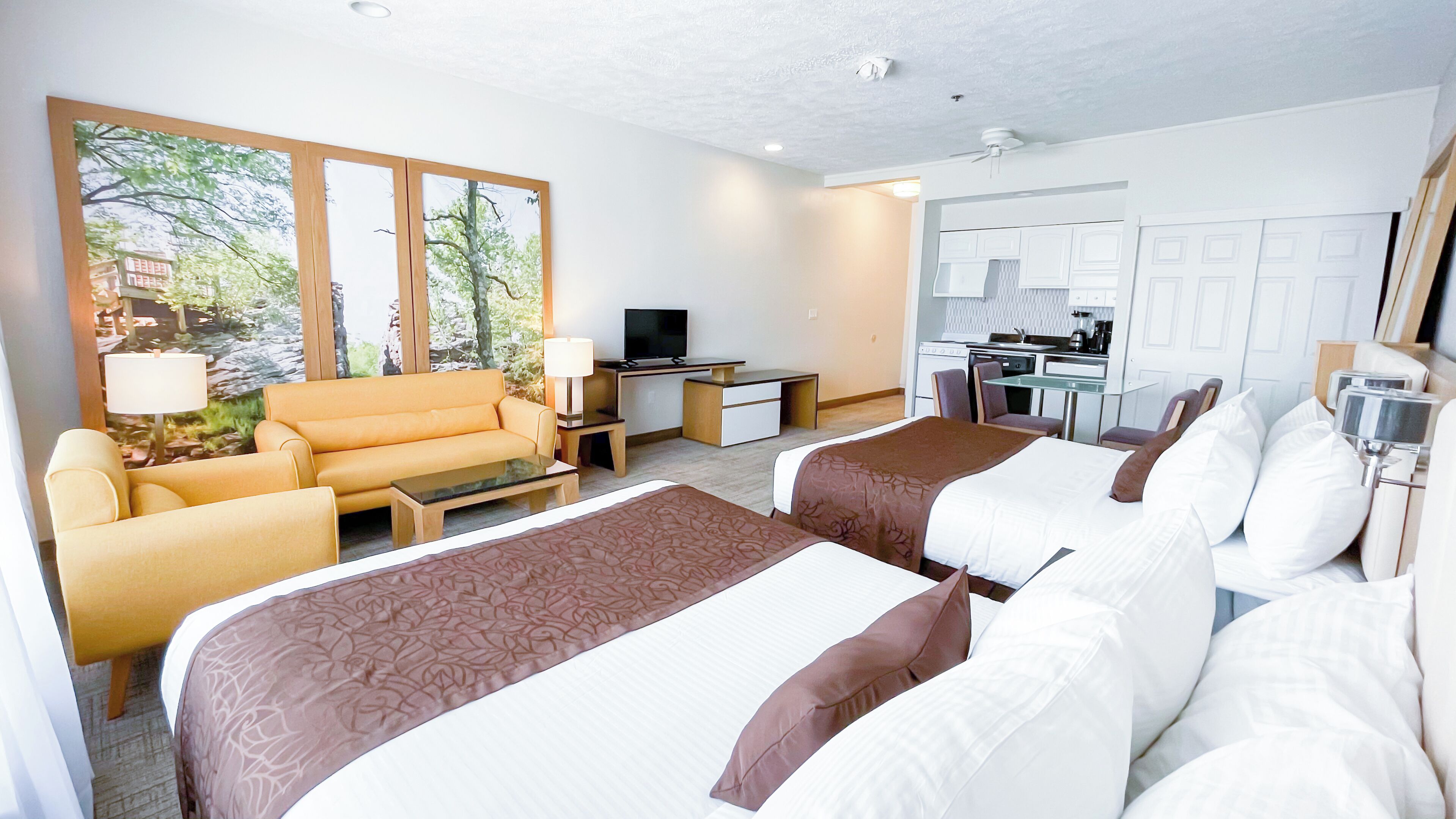 Une chambre d’hôtel avec deux lits, un canapé, un bureau, une télévision et une kitchenette.