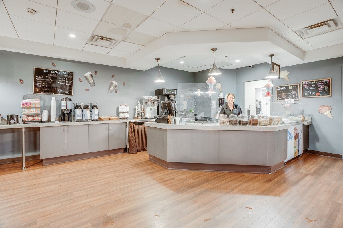 A coffee shop interior with a central counter, espresso machines, and a menu board on the wall.
