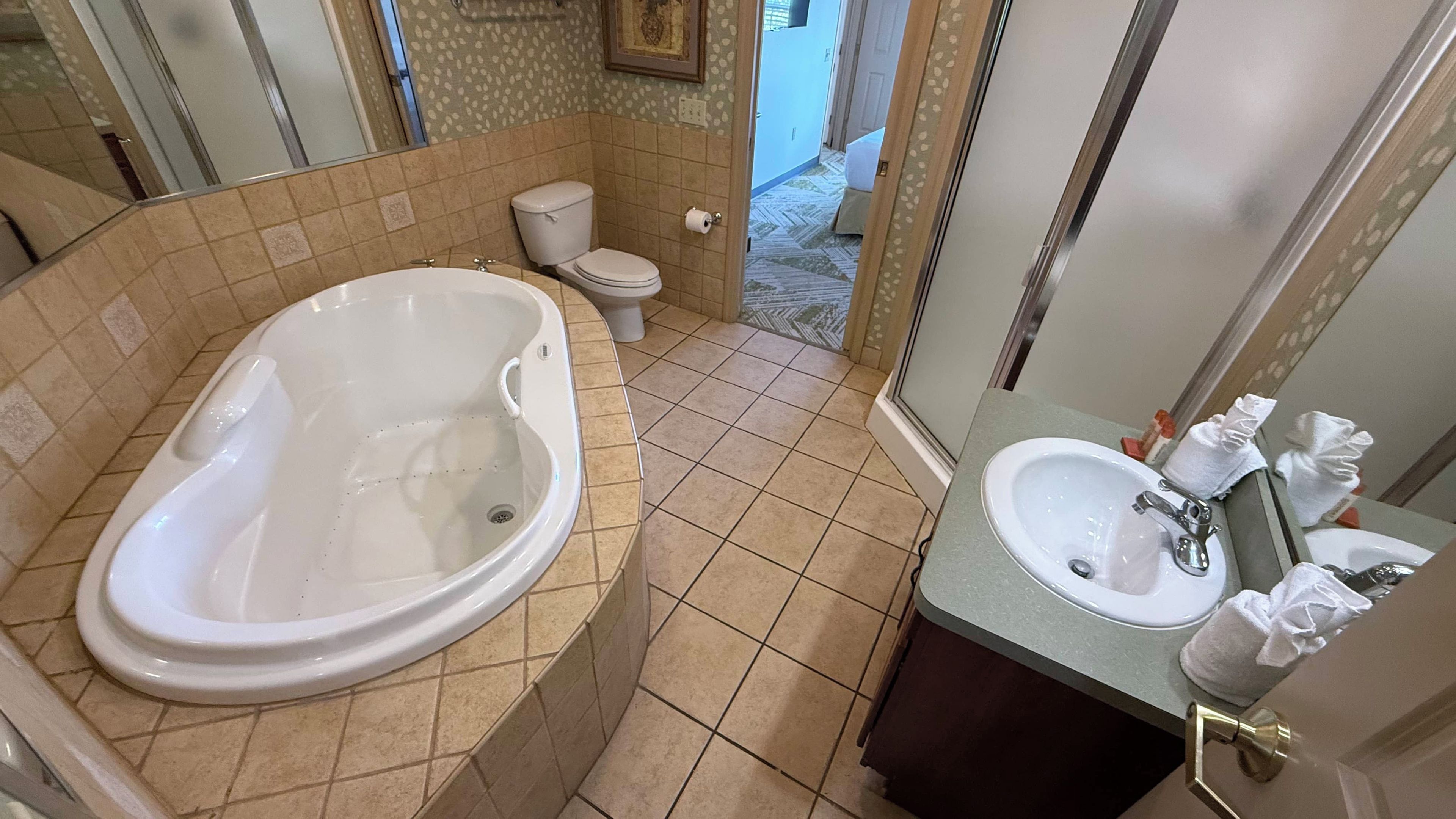 A bathroom with a bathtub, toilet, sink, and a shower area.