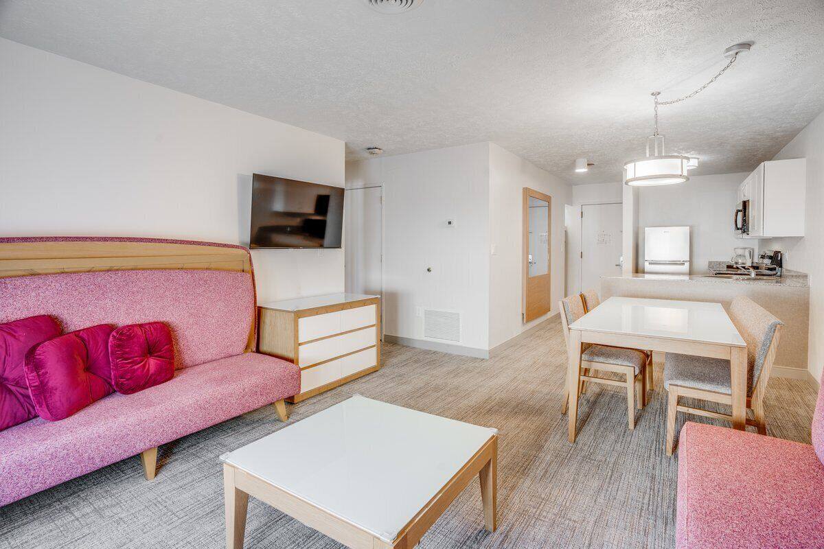 A modern living room with a pink sofa, a white coffee table, and a dining area with a table and chairs.