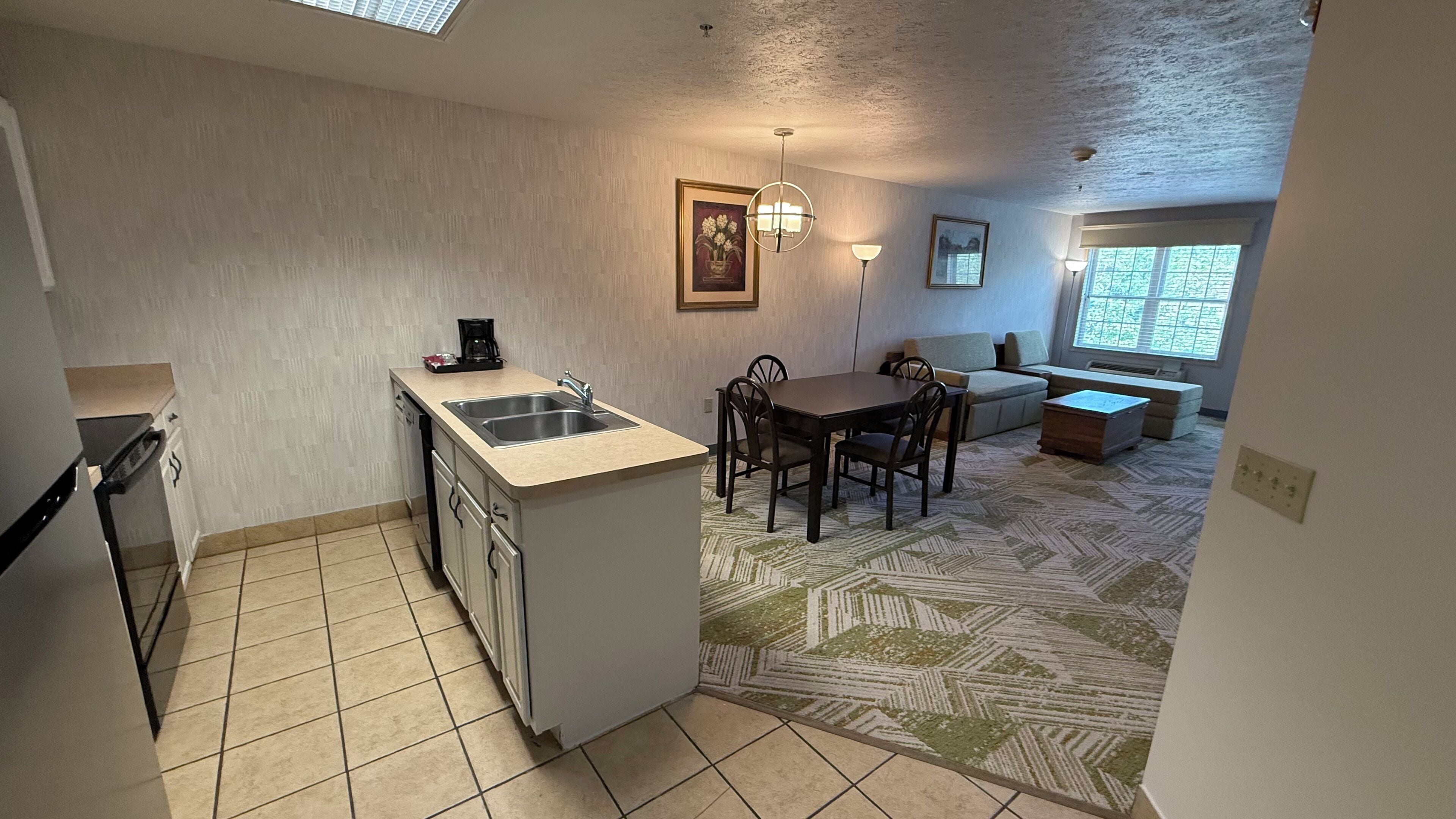 A compact kitchen with a sink, a coffee maker, and a dining area with a table and chairs.