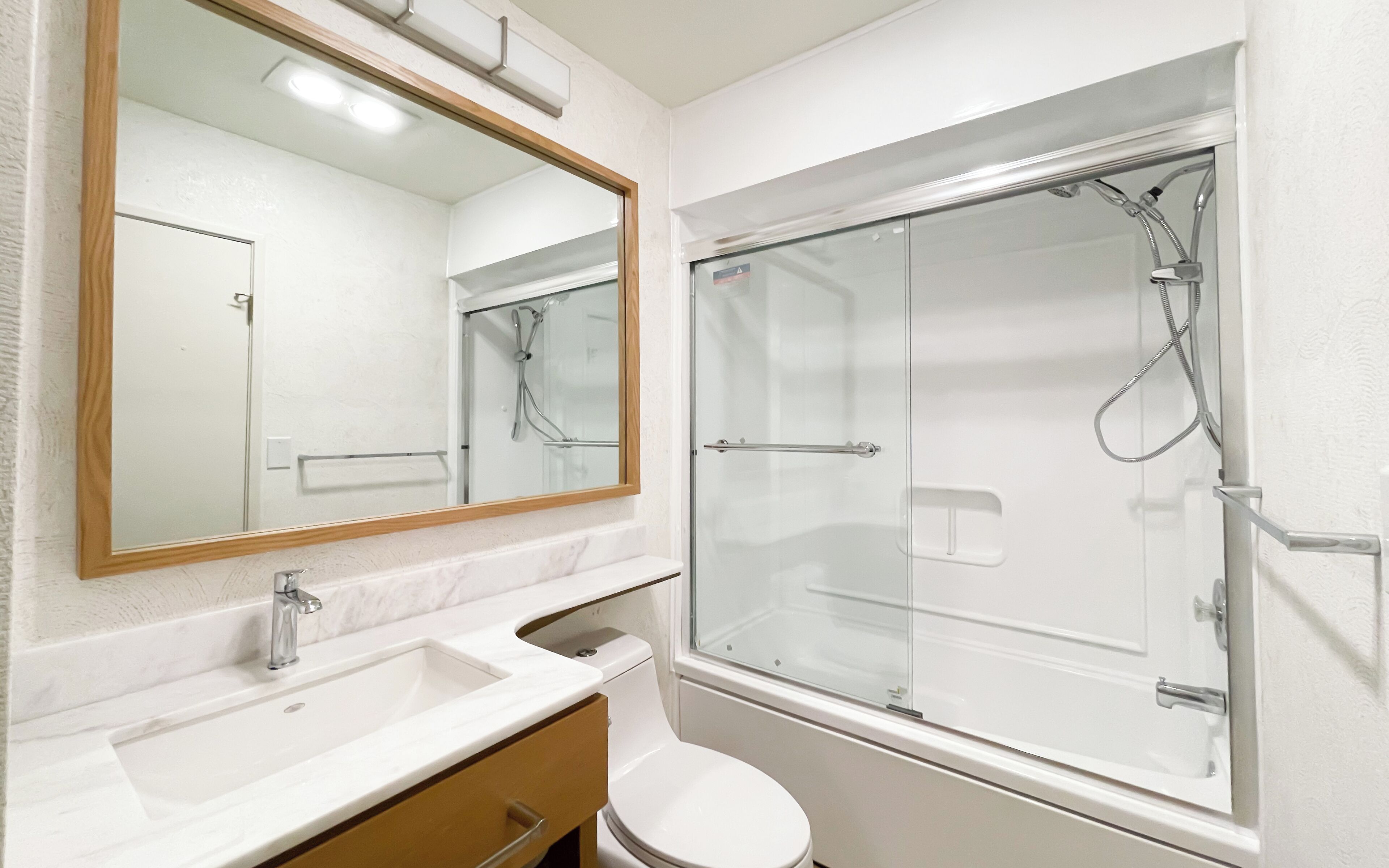A bathroom with a white sink, mirror, and toilet.