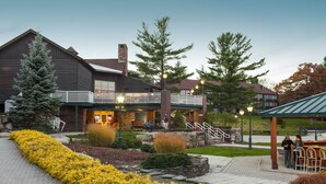 A lodge with a covered outdoor seating area, a stone retaining wall, and a well-maintained garden.