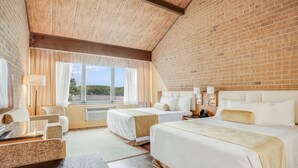 A hotel room with two beds, a desk, and a view of the outdoors.