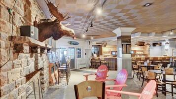 Un restaurante con pared de piedra, cabeza de alce montada y sillas de madera.