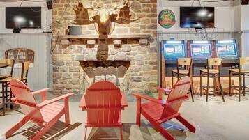 A cozy interior with a stone fireplace, red Adirondack chairs, and a television mounted on the wall.