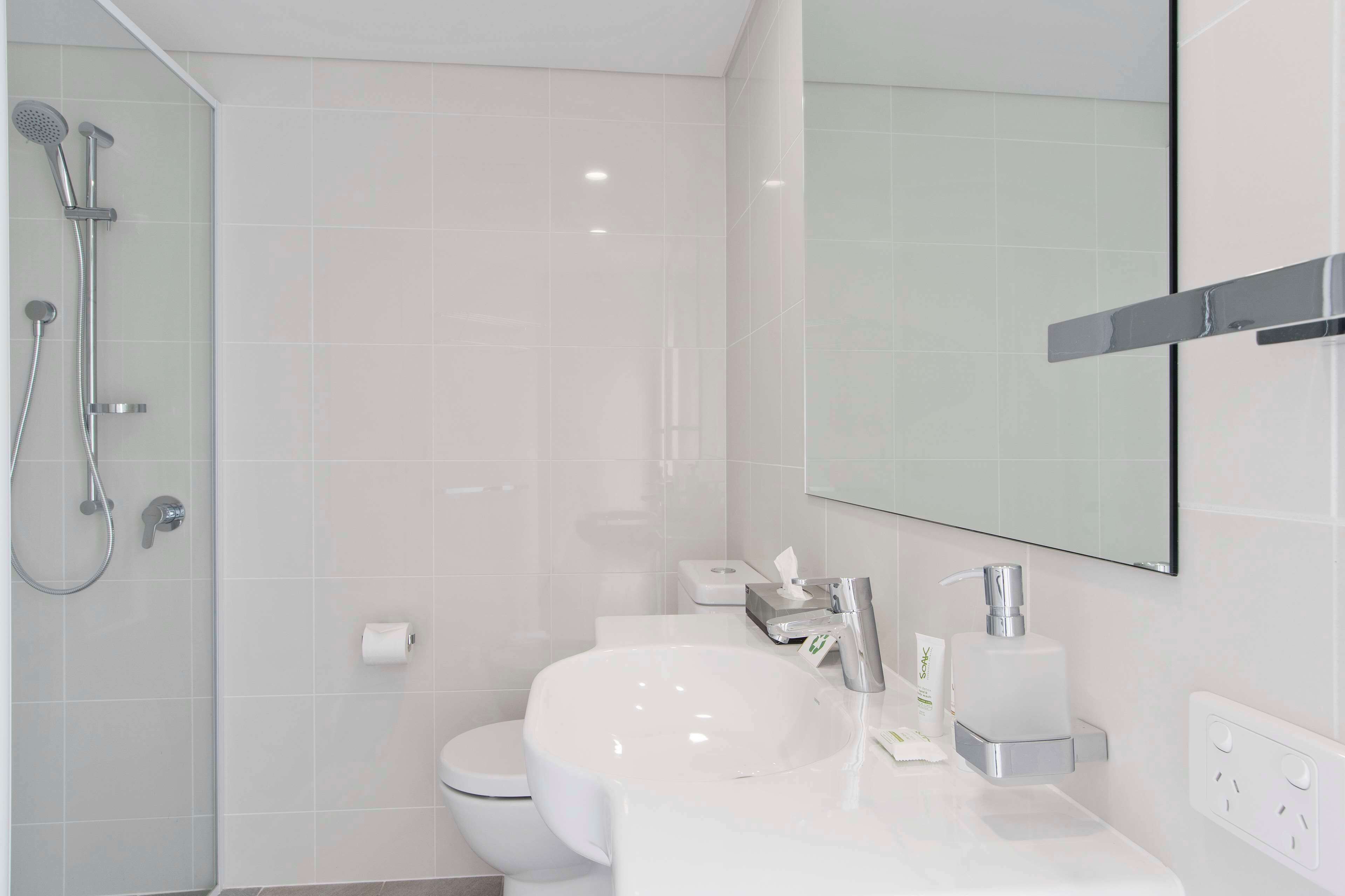 A modern bathroom with a white sink, a toilet, and a shower area.