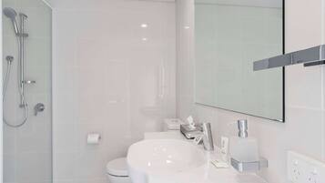 A modern bathroom with a white sink, a toilet, and a shower area.
