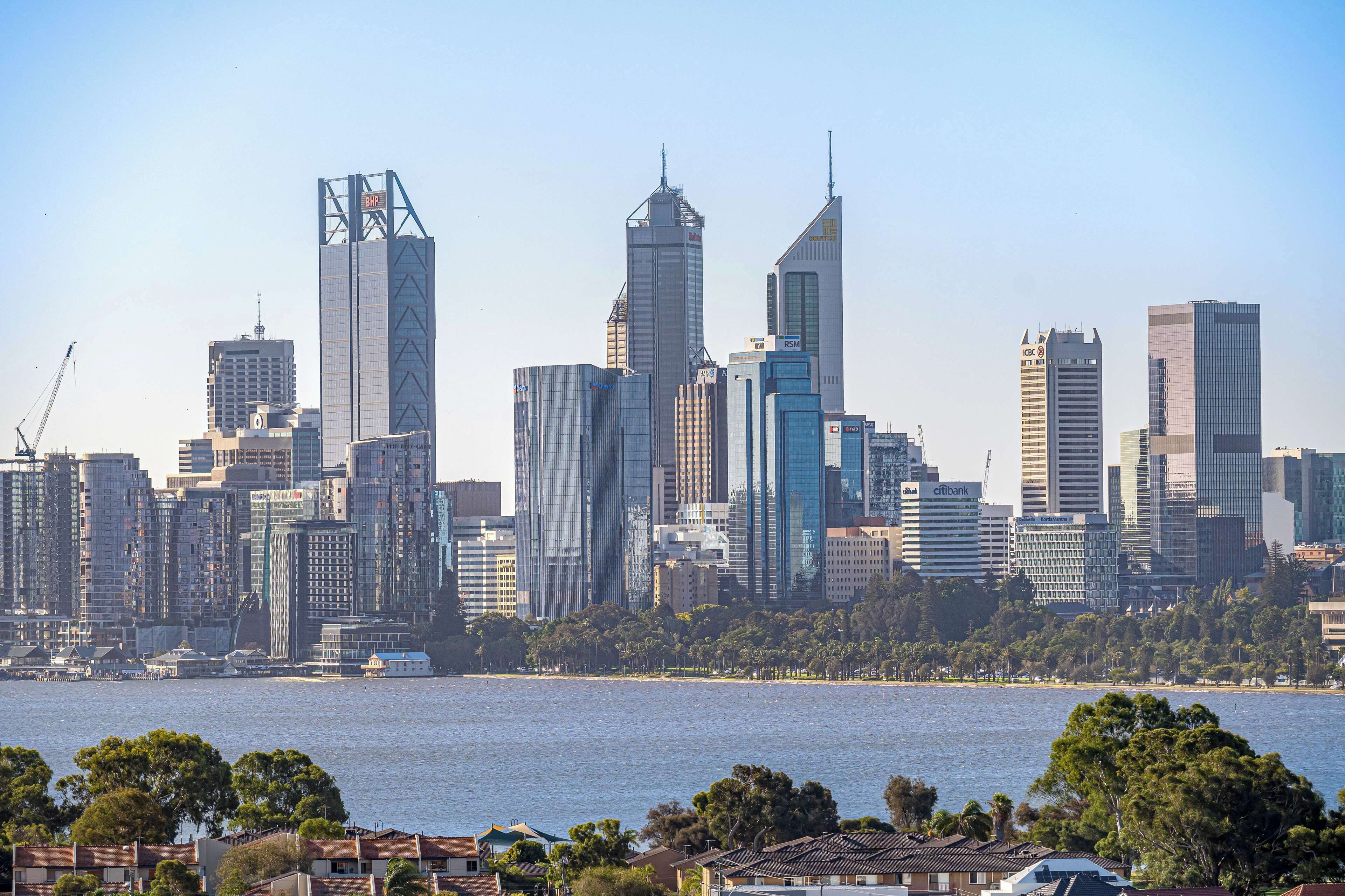 A city skyline with high-rise buildings, a waterfront, and residential houses in the foreground.