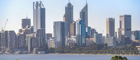 A city skyline with high-rise buildings, a waterfront, and residential houses in the foreground.