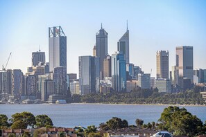 A city skyline with high-rise buildings, a waterfront, and residential houses in the foreground.
