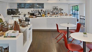 A modern café interior with a central counter, red chairs, wooden beams, and a menu board. - Ojai Valley Inn (Ojai)