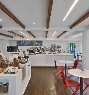 A modern café interior with a central counter, red chairs, wooden beams, and a menu board. - Ojai Valley Inn (Ojai)