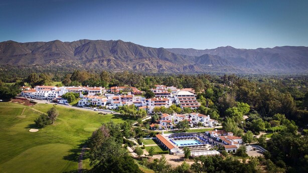 A resort with multiple white buildings, a swimming pool, and a golf course.