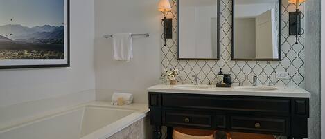 A bathroom with a bathtub, two mirrors, a sink, and a towel rack.
