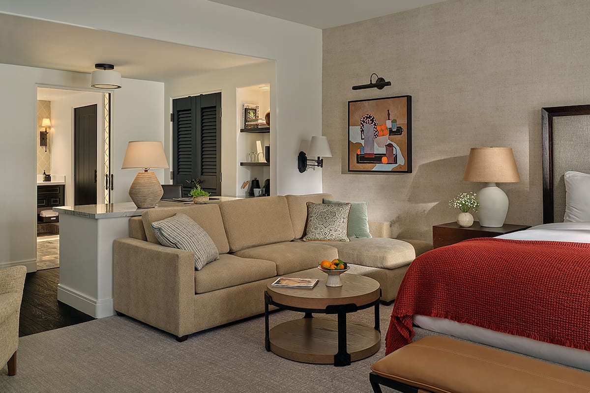 Une chambre d’hôtel avec un canapé, une table basse ronde, un lit et une table de chevet.