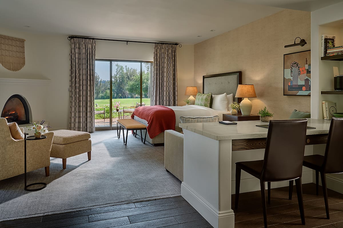 Une chambre d’hôtel équipée d’un lit, d’un bureau, d’une chaise, d’un canapé et d’une cheminée.