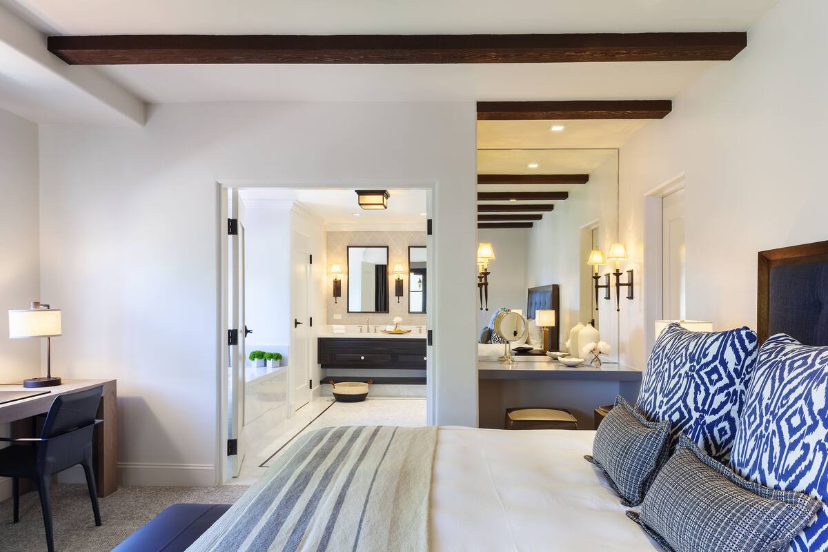 Une chambre d’hôtel moderne, dotée d’un grand lit, d’un bureau et d’une salle de bain visible à travers une porte ouverte.